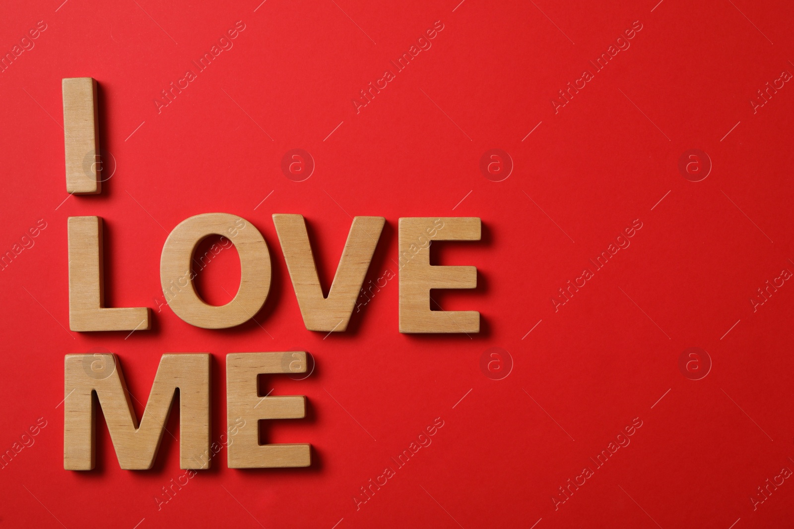 Photo of Phrase I Love Me made of wooden letters on red background, flat lay. Space for text