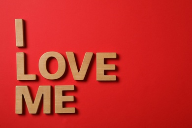 Phrase I Love Me made of wooden letters on red background, flat lay. Space for text