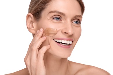 Woman with swatch of foundation on face against white background