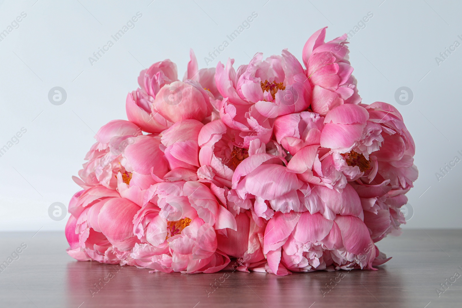 Photo of Beautiful pink peonies on wooden table against white background