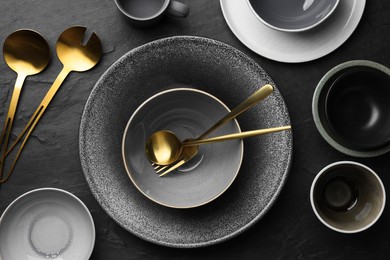 Photo of Setclean tableware on black table, flat lay