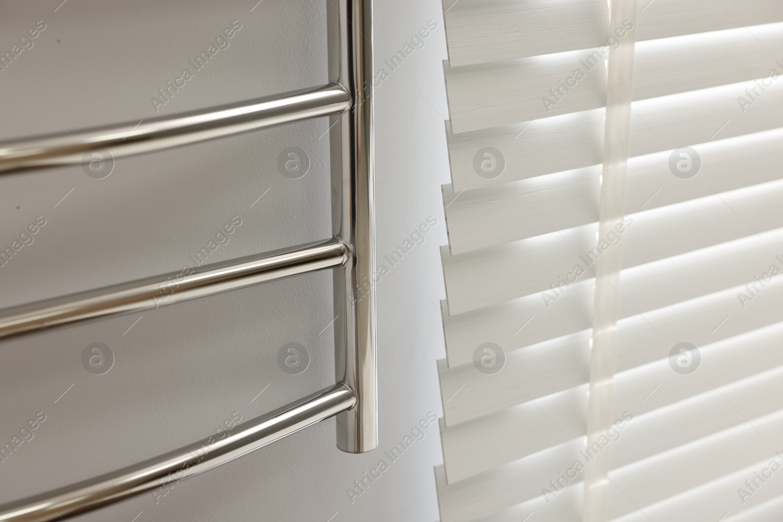 Photo of Heated towel rail on white wall in bathroom, closeup. Space for text
