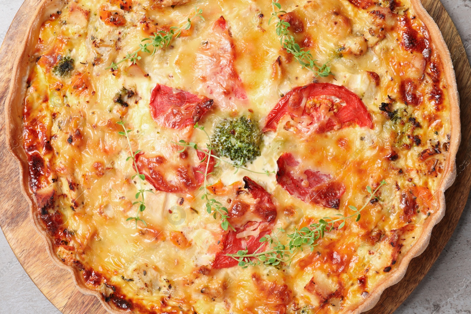 Photo of Tasty quiche with cheese and tomatoes on light grey table, top view