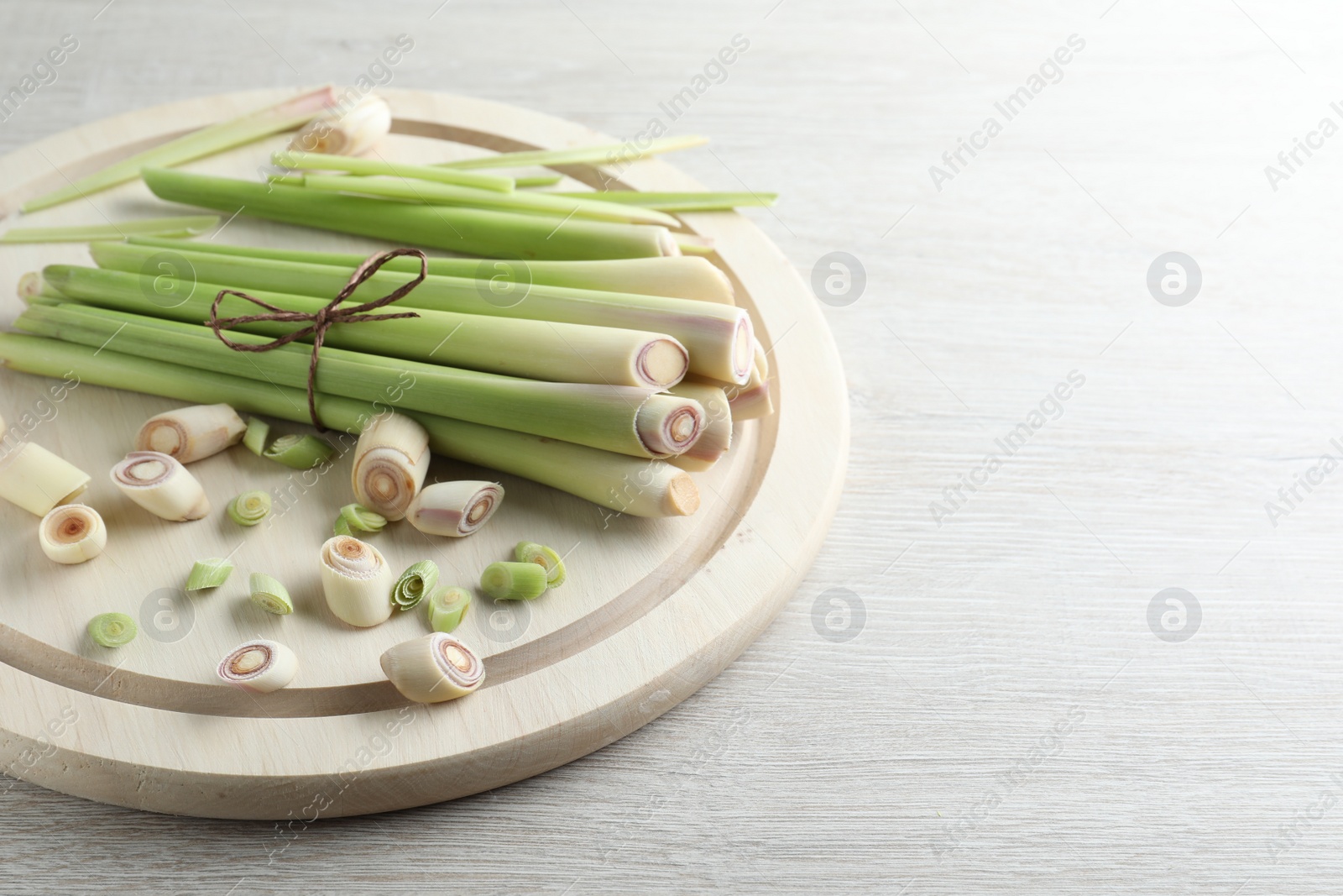 Photo of Whole and cut fresh lemongrass on white wooden table, space for text