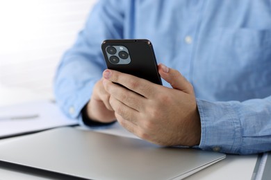 Photo of Man using smartphone at table in office, closeup