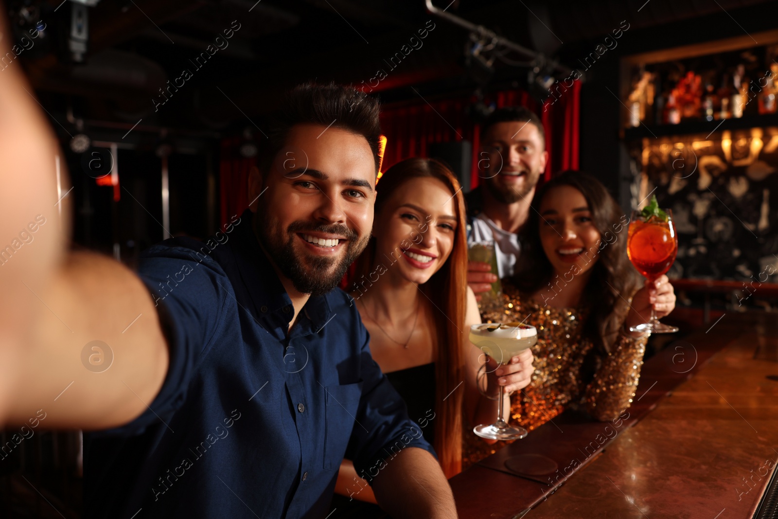 Photo of Happy friends with cocktails taking selfie together in bar