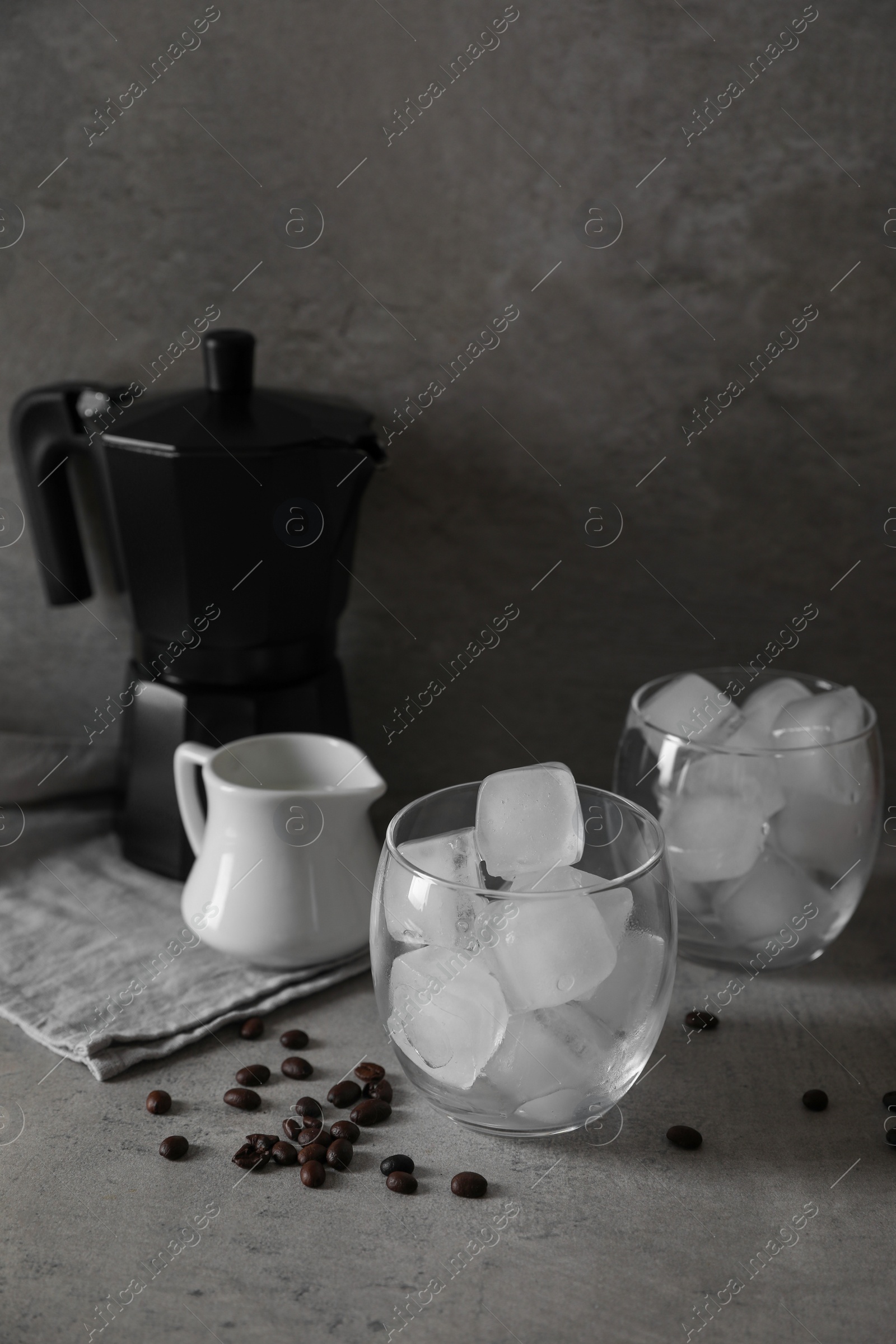 Photo of Making iced coffee. Ice cubes in glasses and ingredients on gray table, closeup