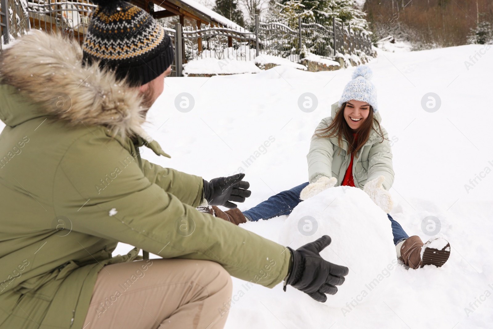 Photo of Happy couple making ball for snowman outdoors. Winter vacation