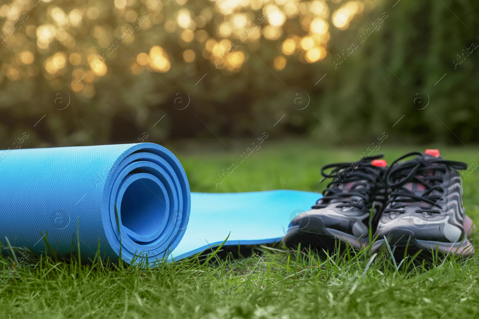 Photo of Blue karemat or fitness mat and sneakers on green grass outdoors