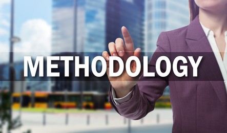 Image of Woman pointing at word Methodology on virtual screen, closeup. Office buildings on background