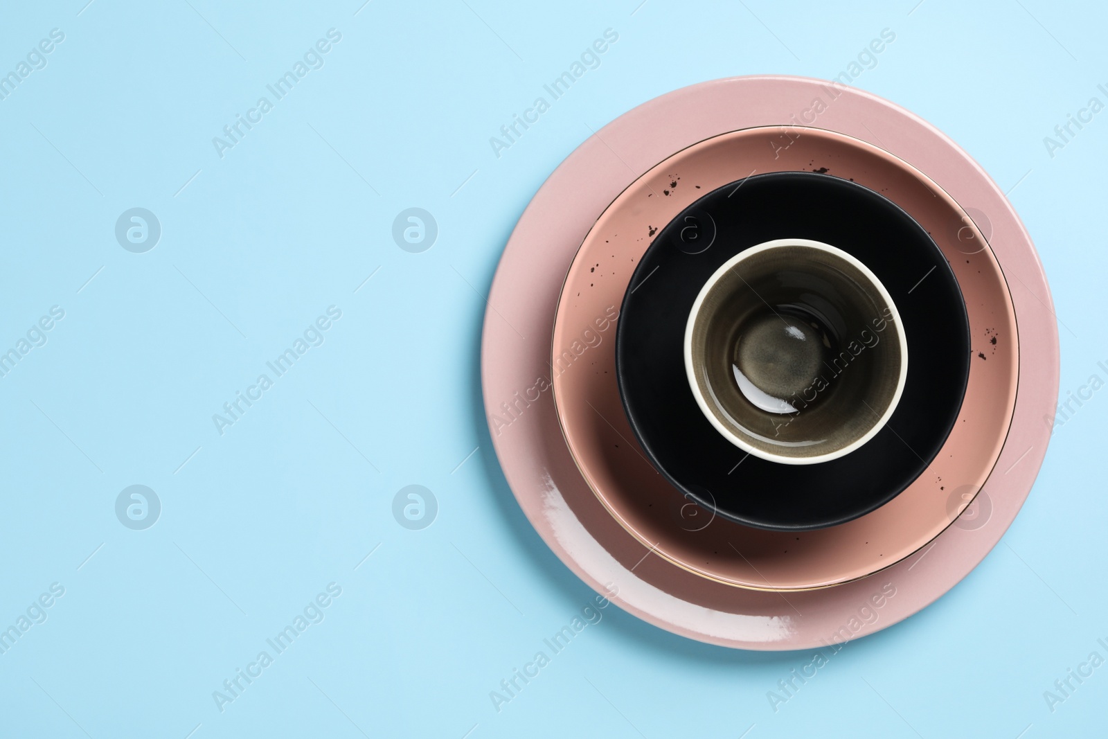 Photo of Stack of clean dishes on light blue background, top view. Space for text