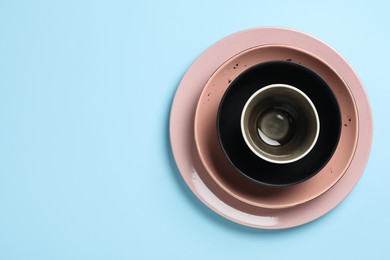 Photo of Stack of clean dishes on light blue background, top view. Space for text