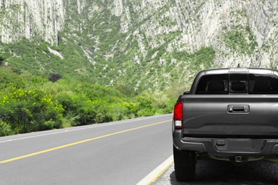 Picturesque view of big mountains and trees near road with black car, space for text