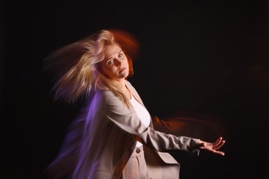 Young woman performing contemporary dance on black background, motion blur effect