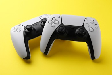 Two wireless game controllers on yellow background