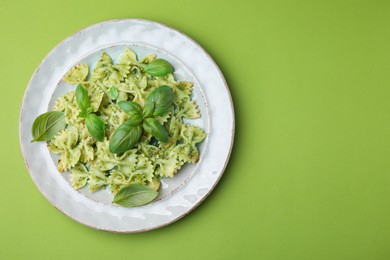 Photo of Delicious pasta with pesto sauce and basil on light green background, top view. Space for text