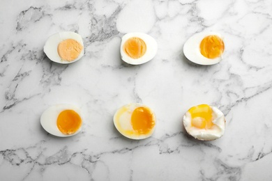 Photo of Various types of boiled eggs on marble background, flat lay. Cooking time