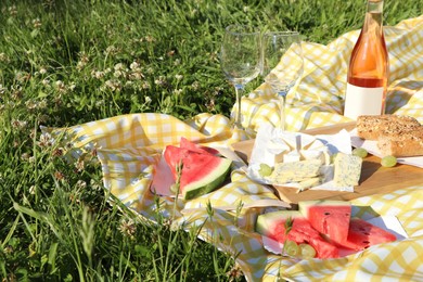 Photo of Picnic blanket with delicious food and wine on green grass outdoors