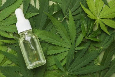 Photo of Bottle of CBD oil or THC tincture on fresh hemp leaves, top view. Space for text