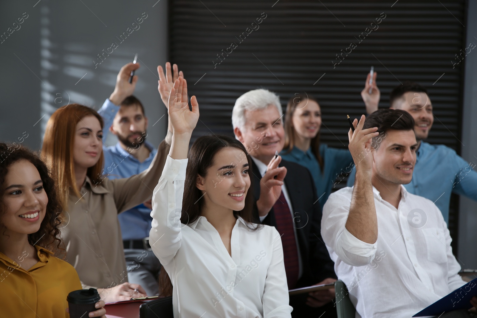 Photo of People raising hands to ask questions at seminar in office