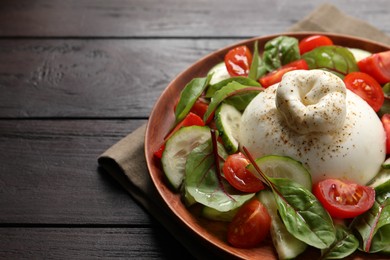 Photo of Delicious burrata salad served on wooden table. Space for text