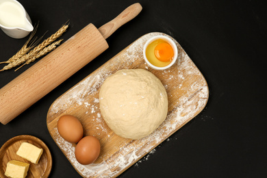 Photo of Flat lay composition with dough and other ingredients on black table. Baking pie