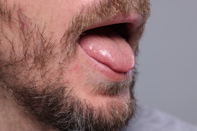 Closeup view of man showing his tongue on grey background