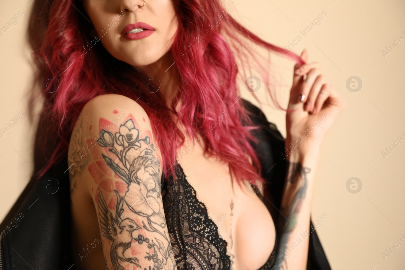 Photo of Beautiful woman with tattoos on body against beige background, closeup