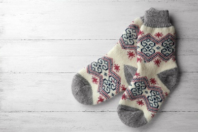 Photo of Knitted socks on white wooden background, flat lay