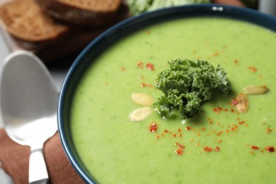 Photo of Tasty kale soup with pumpkin seeds on table, closeup