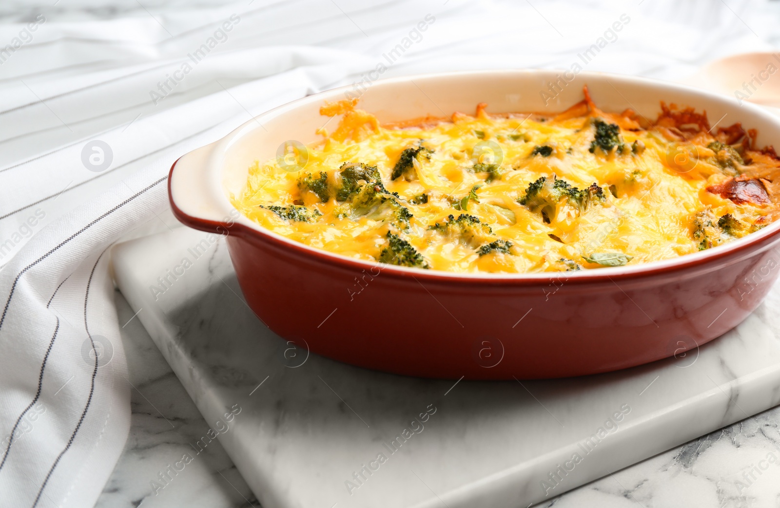 Photo of Tasty broccoli casserole in baking dish on white marble table