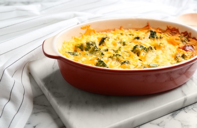 Photo of Tasty broccoli casserole in baking dish on white marble table