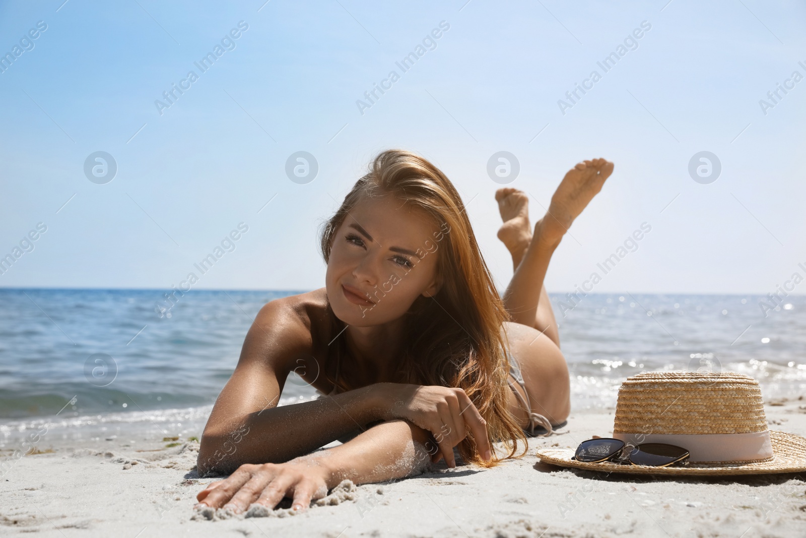 Photo of Attractive woman in bikini lying on sandy beach near sea