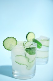 Photo of Tasty fresh cucumber water with mint on light blue background