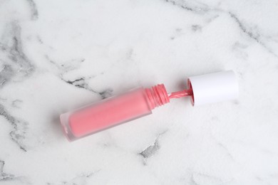 Photo of Pink lip gloss on white marble table, top view