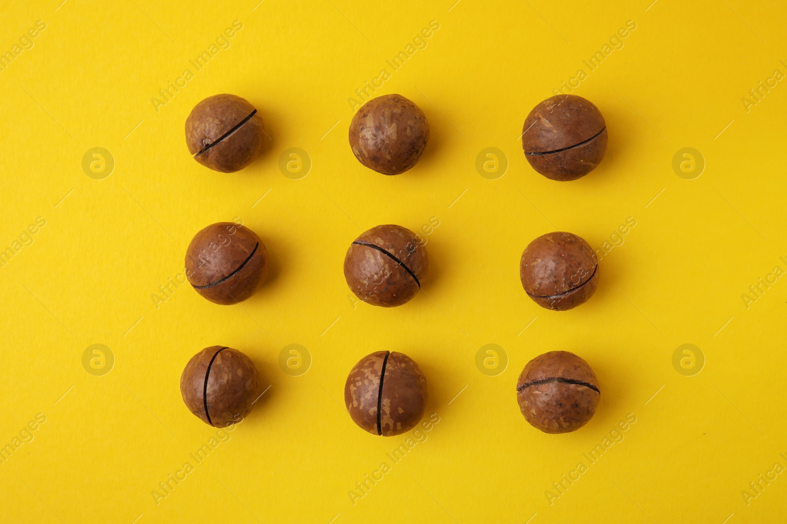 Photo of Tasty Macadamia nuts on yellow background, flat lay