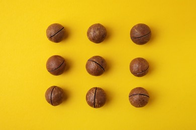 Tasty Macadamia nuts on yellow background, flat lay