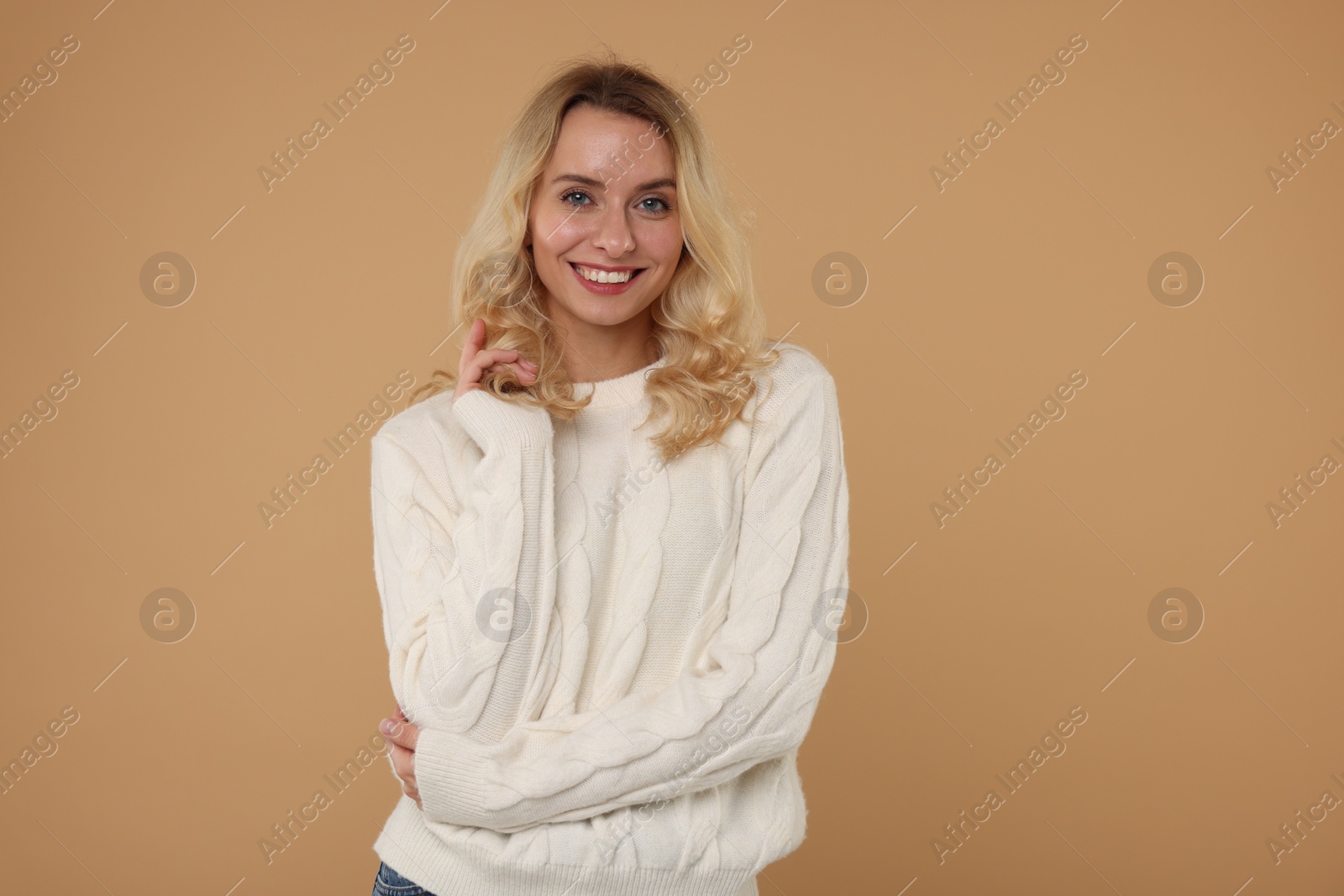 Photo of Happy woman in stylish warm sweater on beige background