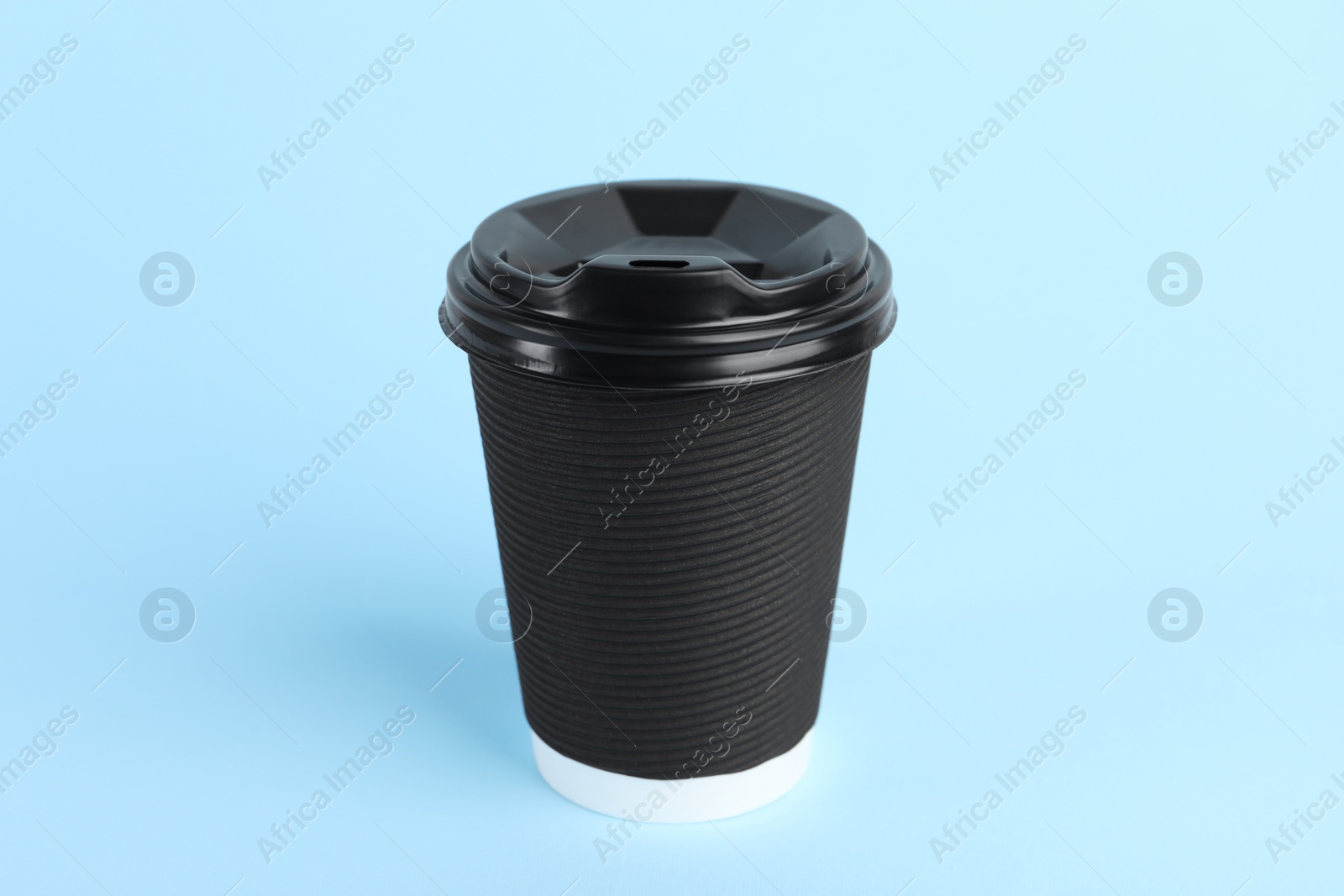 Photo of Black paper cup with plastic lid on light blue background. Coffee to go