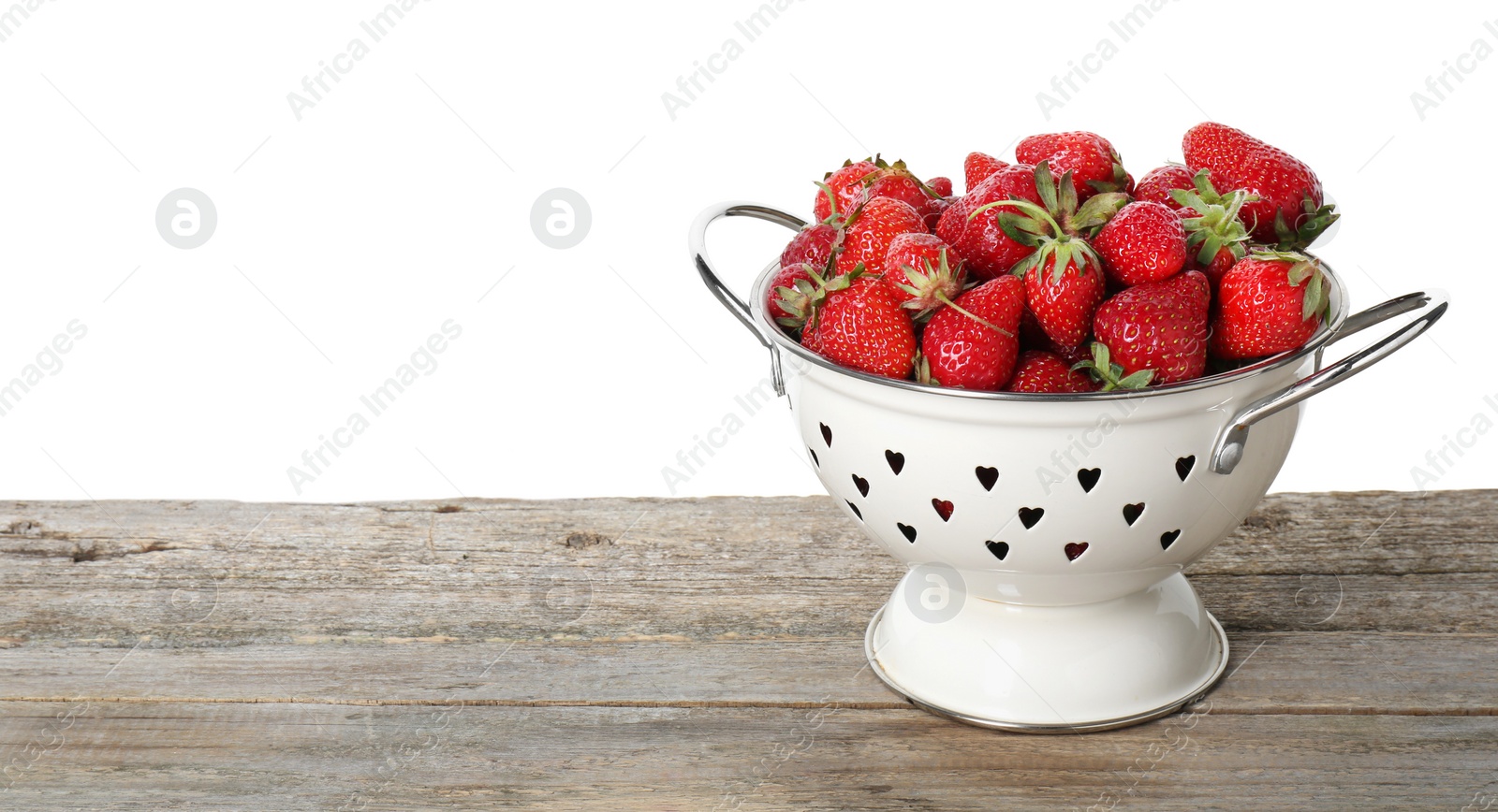 Photo of Colander with fresh strawberries on wooden table against white background. Space for text