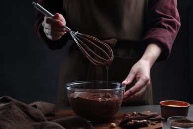 Photo of Woman with whisk mixing delicious chocolate cream at table, closeup