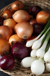 Photo of Different kinds of onions on wicker mat, closeup