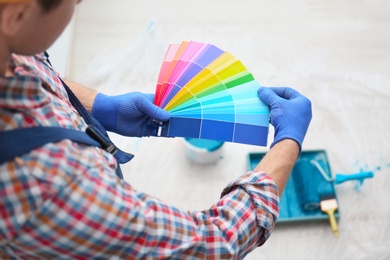 Male decorator holding color palette samples indoors