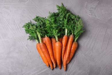 Photo of Bunch of fresh carrots on stone background, top view