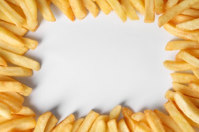 Photo of Frame of delicious french fries on white background, flat lay. Space for text