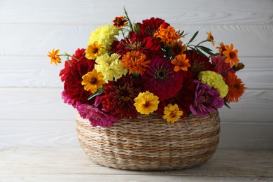 Beautiful wild flowers in wicker basket on light wooden table