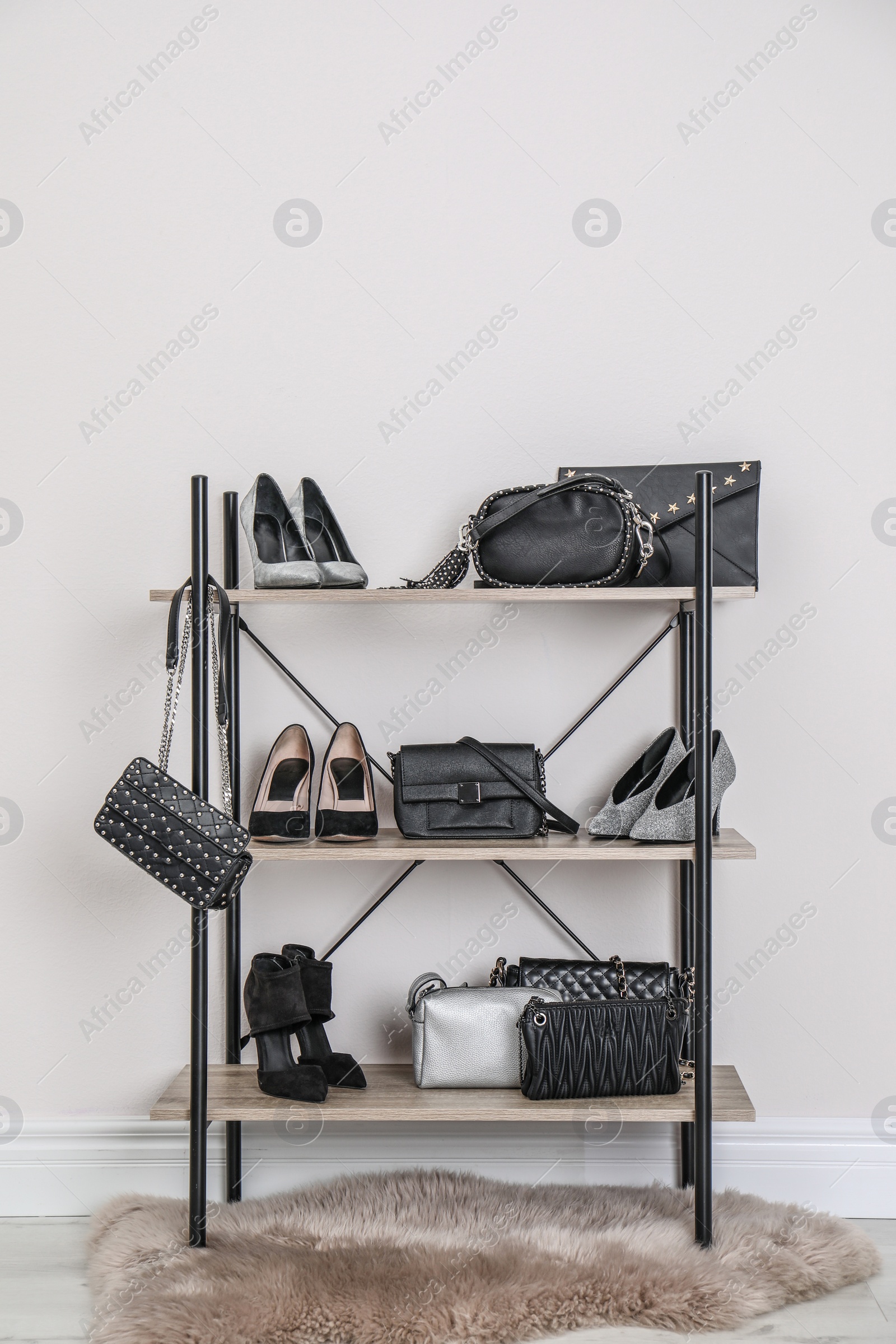 Photo of Shelving unit with stylish shoes and purses near white wall. Element of dressing room interior