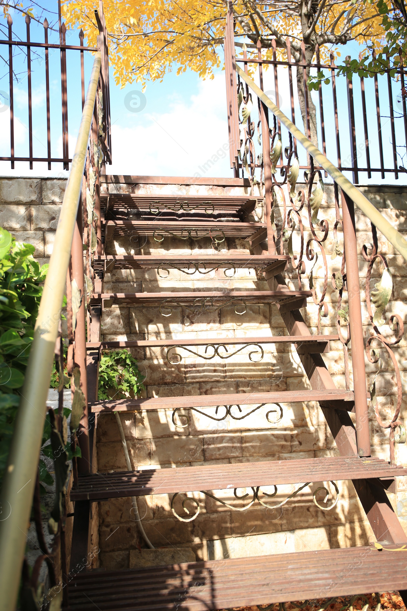 Photo of View of old metal stairs with handrails near brick wall outdoors