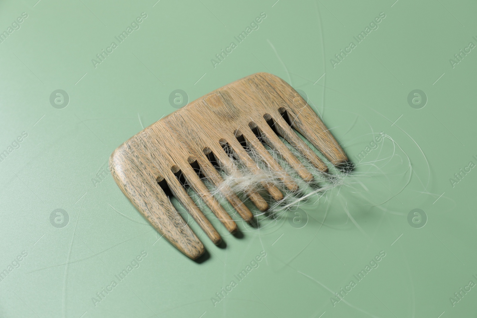 Photo of Comb with lost hair on green background