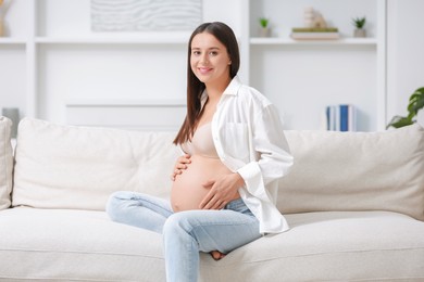 Photo of Beautiful pregnant woman sitting on sofa at home